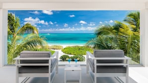 Habitación con vista a la playa, dos sillas, una mesita y dos bebidas.
