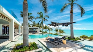 Un resort moderno con piscina, sillas de descanso y palmeras.
