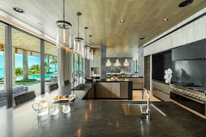 A modern kitchen with a large island, stainless steel appliances, and a view of the pool.