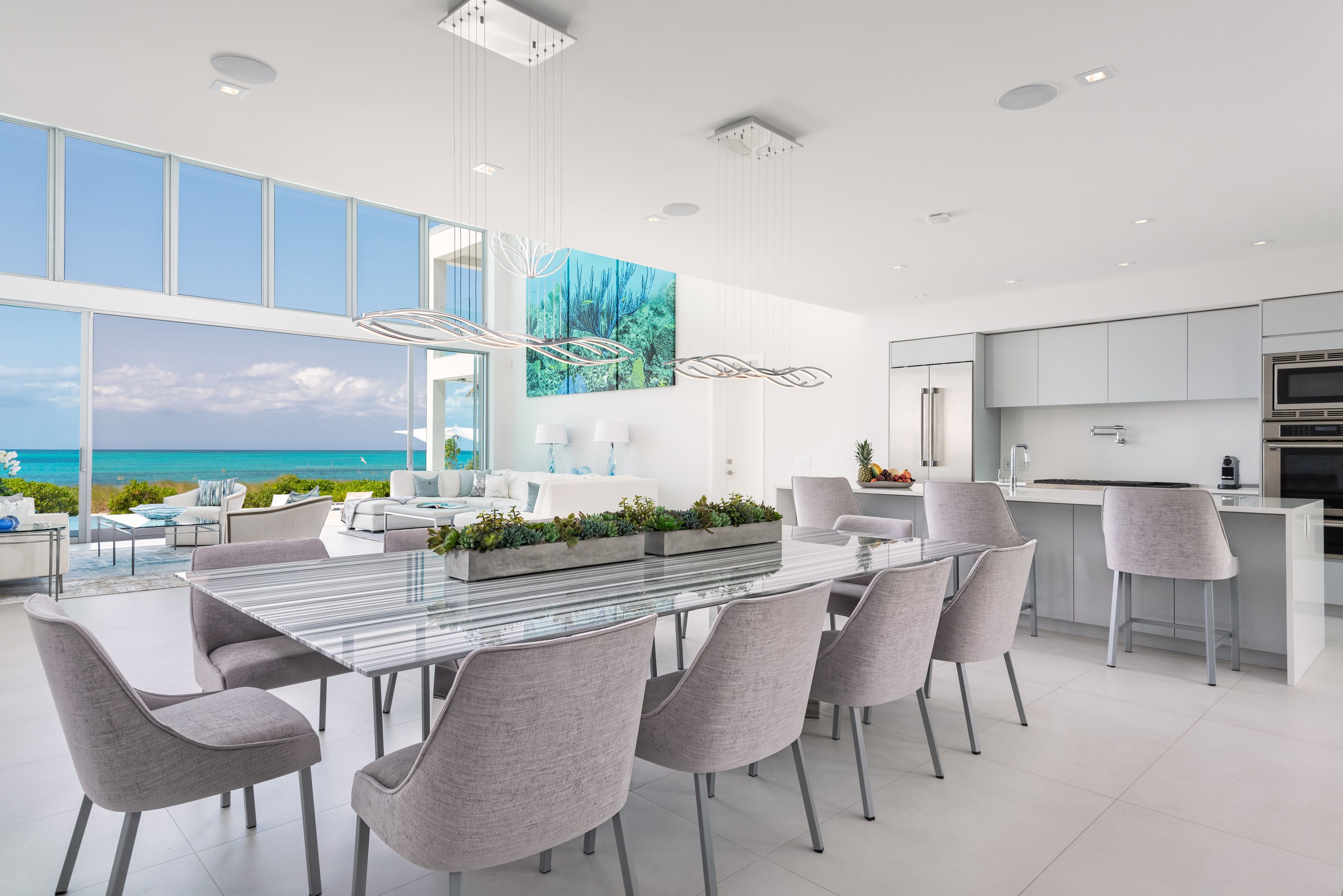 A modern kitchen with a large island, white cabinetry, and a view of the ocean.