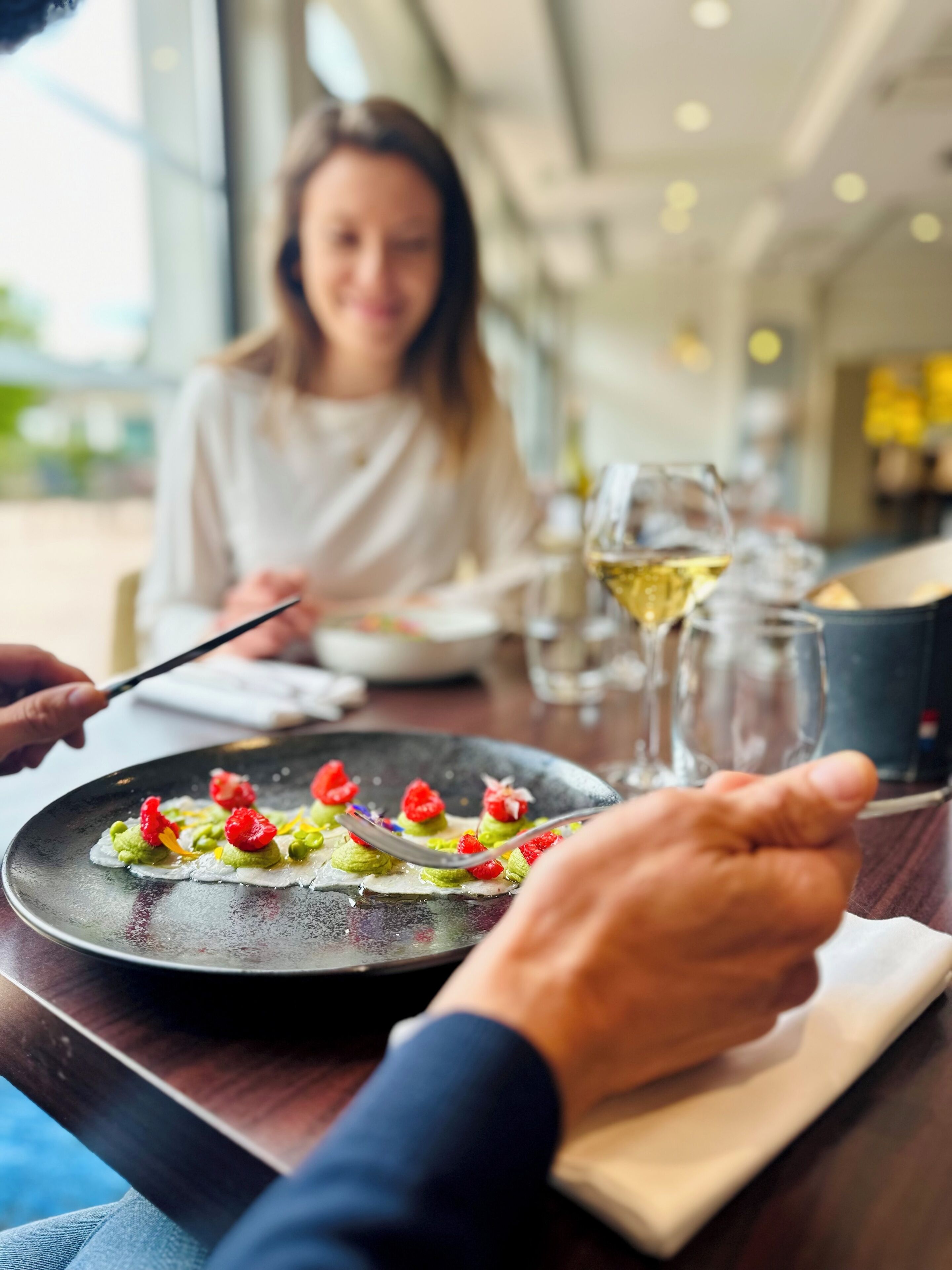 A dining table with a plate of food, a wine glass, and a water glass.