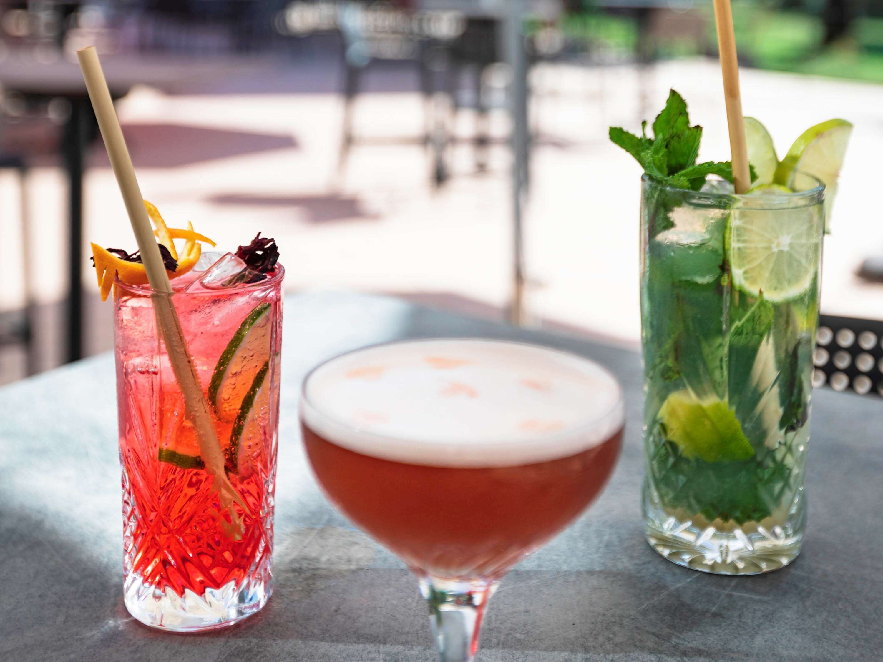 Two drinks on a table with a blurred outdoor background.