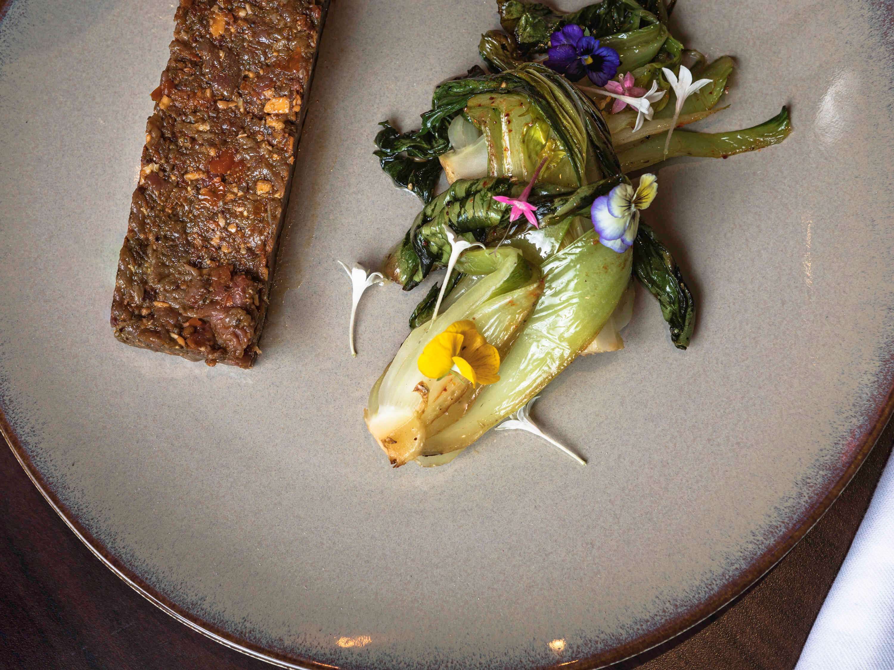 A plate with a piece of meat and a vegetable dish.