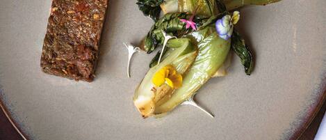 A plate with a piece of meat and a vegetable dish.