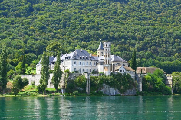 A castle-like building with multiple towers, situated on a cliff by a river.