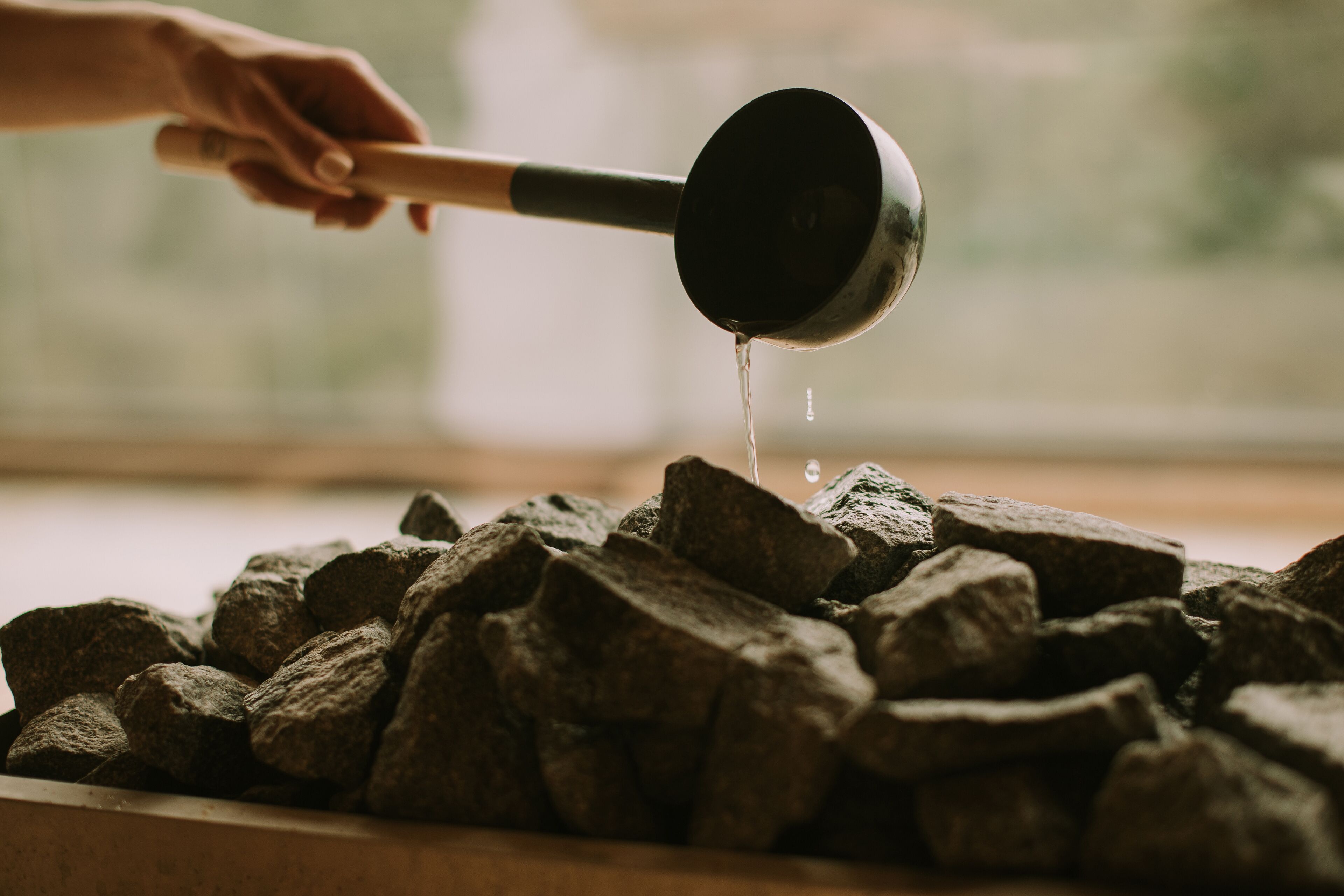 A hand holding a ladle over a pile of charcoal.