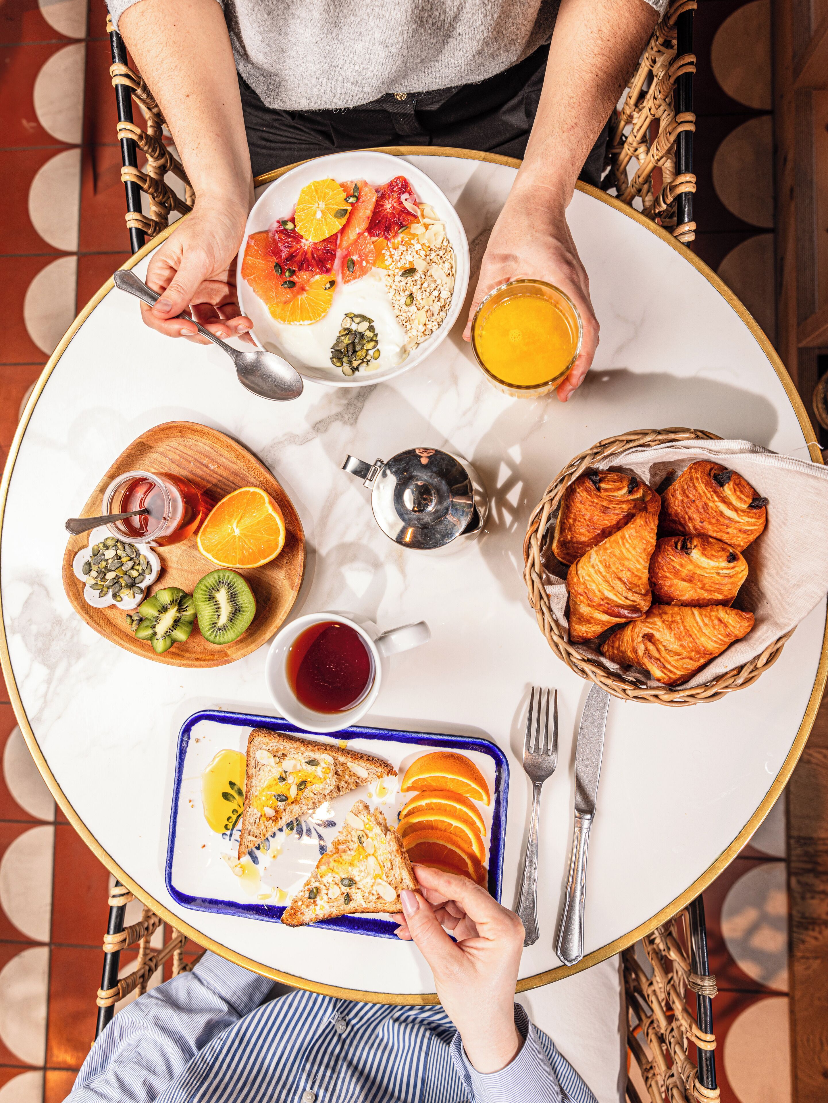 A breakfast setting with a variety of foods including toast, pastries, and fruit, arranged on a round table.