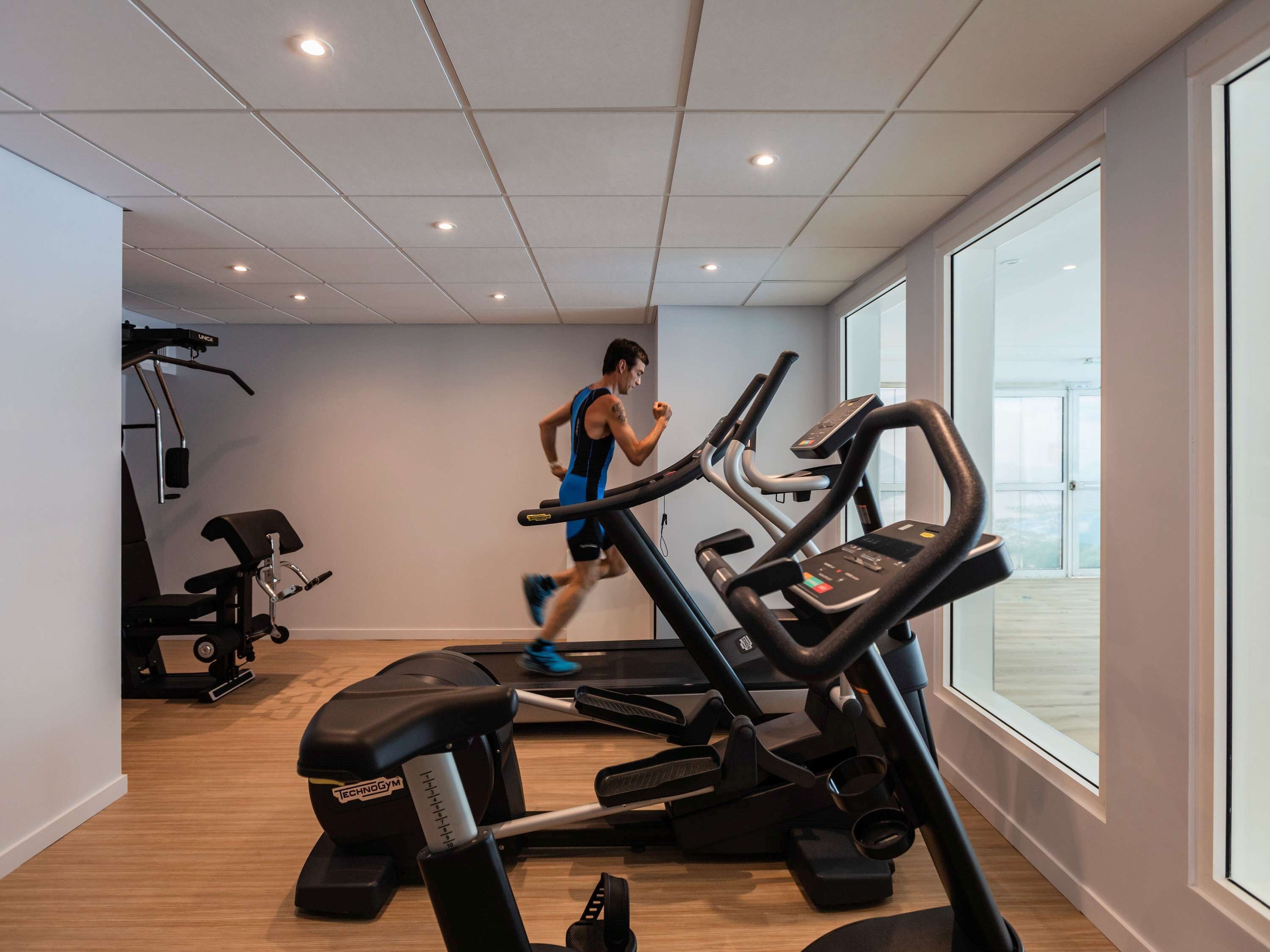 Un gimnasio con cintas de correr, una banca y una máquina de pesas.