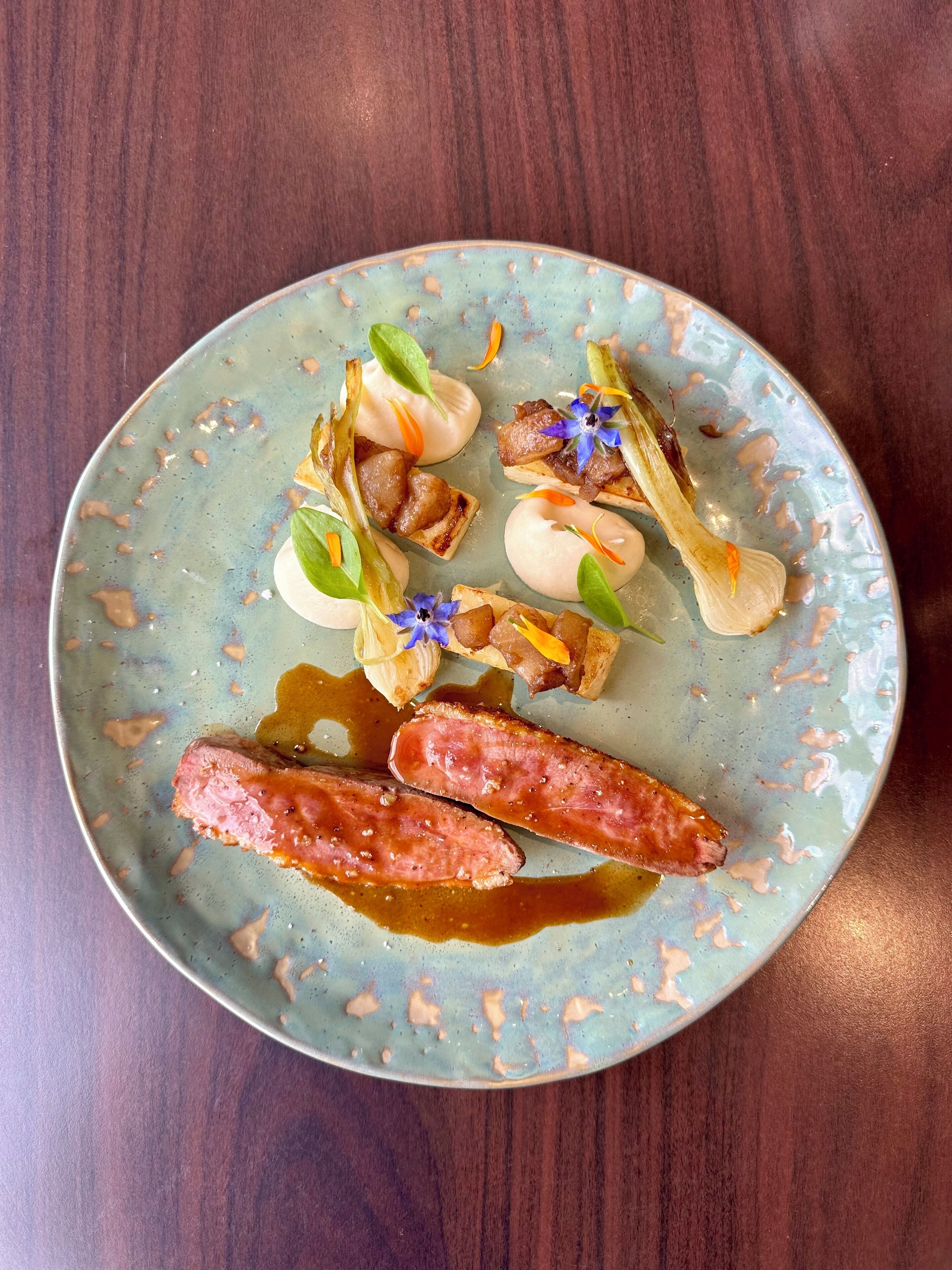 A plate with various food items including sausages, vegetables, and a sauce.