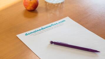 A wooden table with a paper displaying a website URL, a purple pen, and a glass of water.