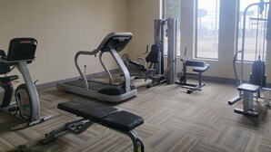 Un gimnasio con cintas de correr, una banca y máquinas de pesas.
