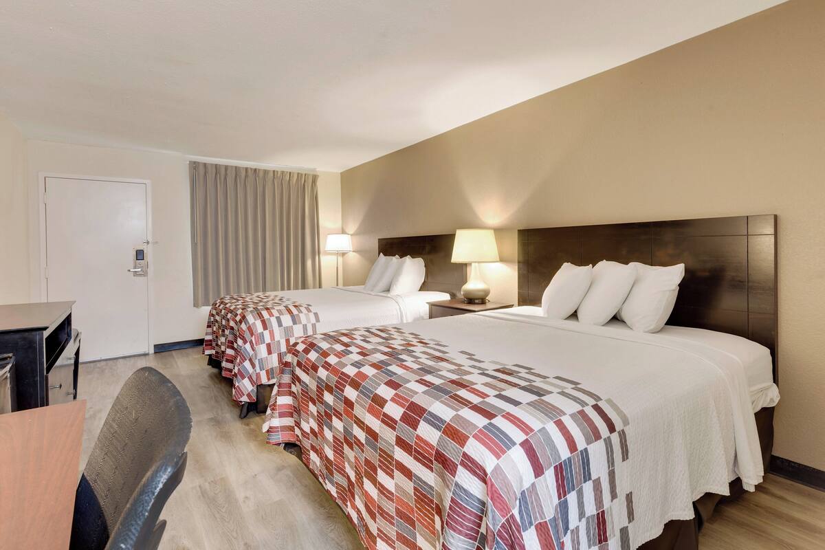 Ein Hotelzimmer mit zwei Betten, einem Schreibtisch und einem Stuhl.