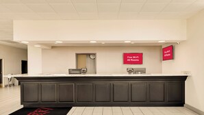 A reception area with a dark counter, a clock, and signs indicating free Wi-Fi in all rooms.