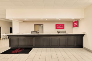A reception area with a dark counter, a clock, and signs indicating free Wi-Fi in all rooms. - Red Roof Inn Gulfport - Biloxi Airport (Gulfport)