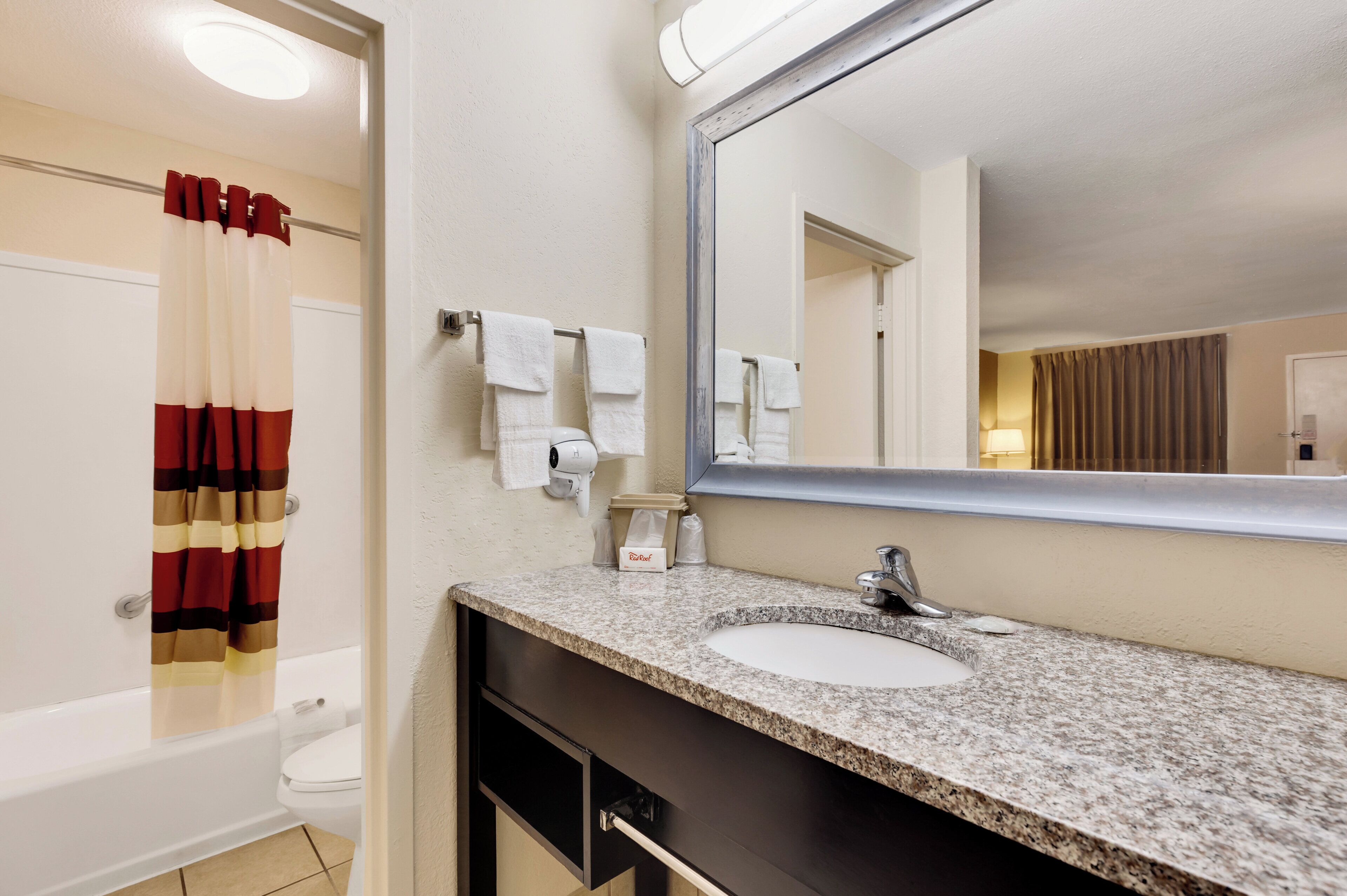 A bathroom with a sink, mirror, towel rack, and a shower curtain.
