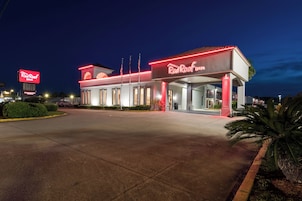 Un Red Roof Inn con un letrero grande, estacionamiento y una entrada bien iluminada.