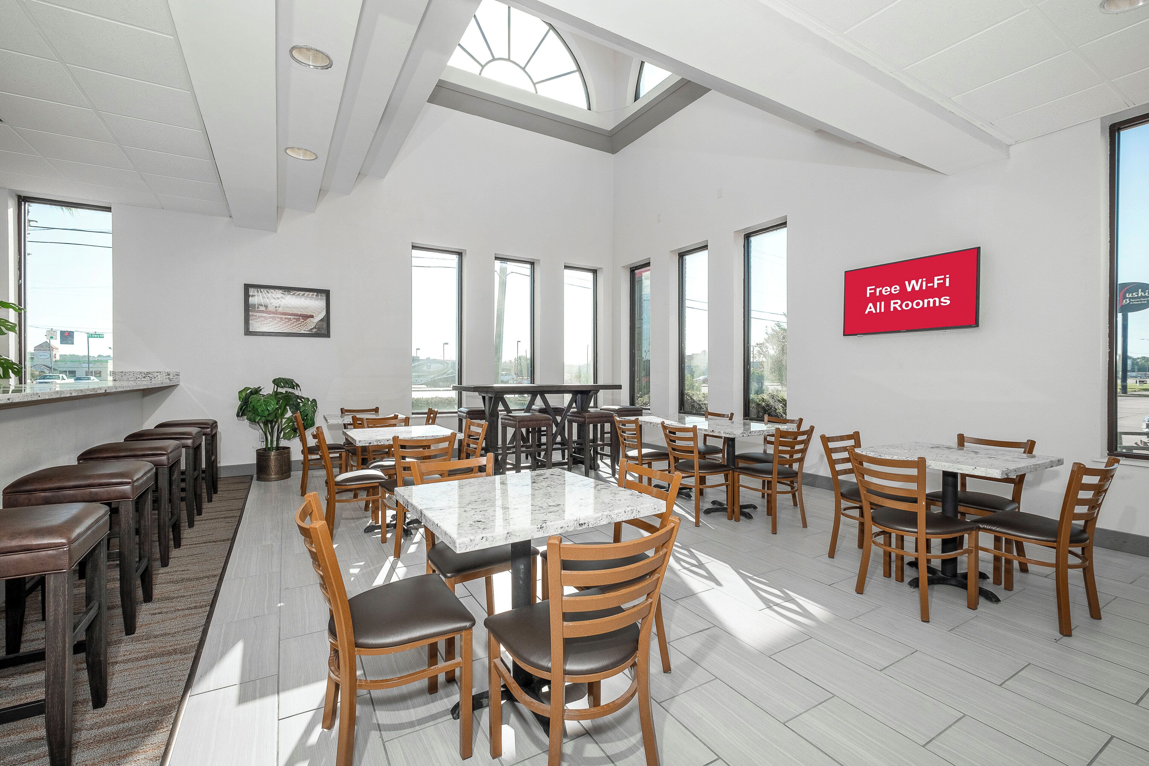 Un grand espace dédié à la salle à manger, avec plusieurs tables et chaises, de grandes fenêtres et un panneau indiquant que le Wi-Fi est disponible gratuitement.