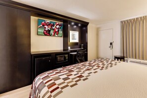 A hotel room with a large bed, a flat-screen TV mounted on the wall, a desk with a chair, and a door with a curtain. - Red Roof Inn Gulfport - Biloxi Airport (Gulfport)