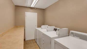 A laundry room with a white door, two washing machines, and a dryer.