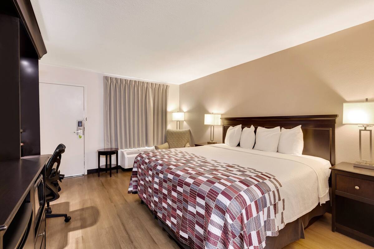 Ett hotellrum med en säng, sänglampor, ett skrivbord och en stol.