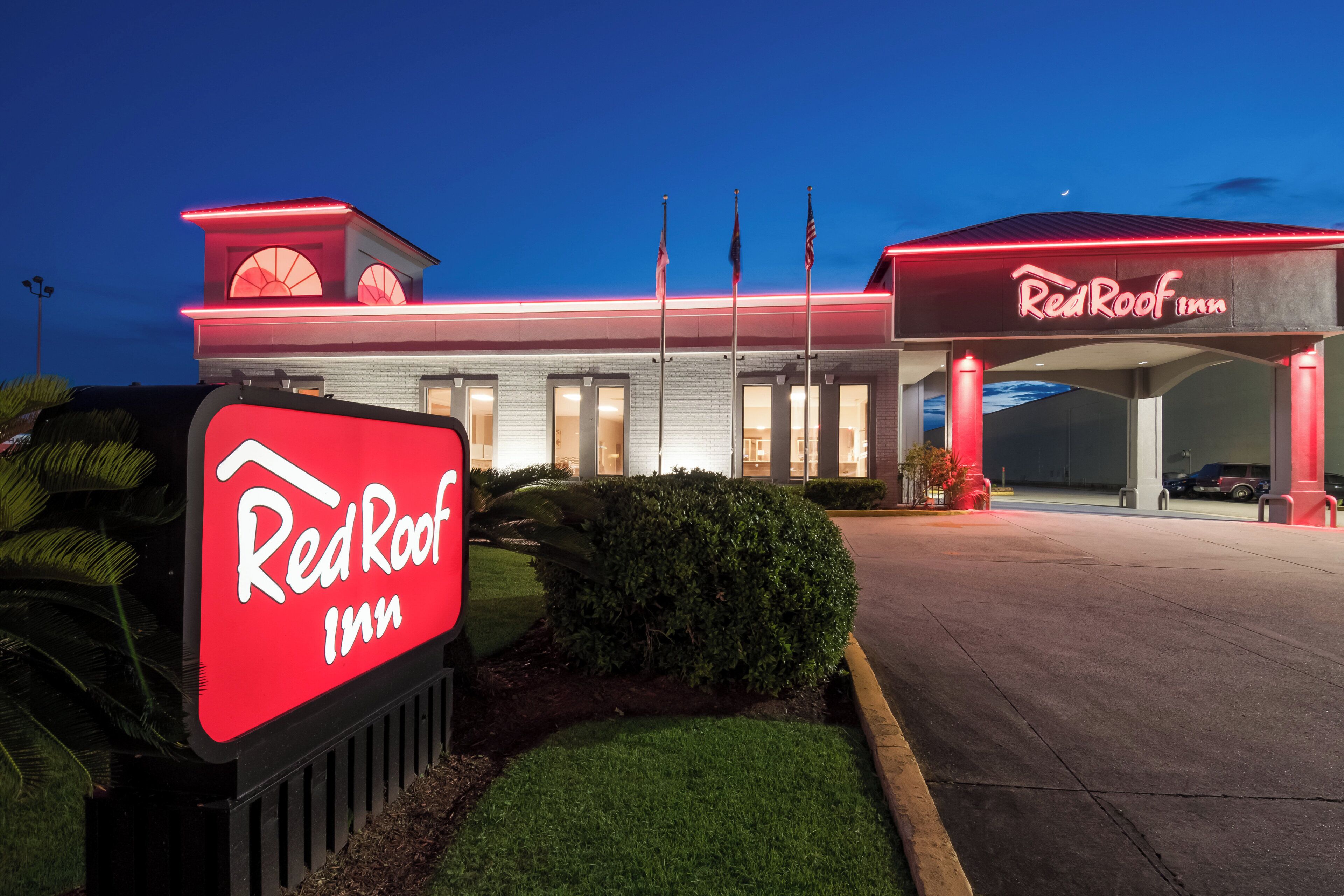 Un hôtel Red Roof Inn, reconnaissable à son grand panneau rouge, son parking et l’entrée de l’établissement.