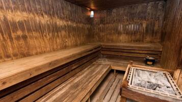 A sauna with wooden benches and a stone heating area.