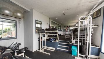 A gym with weightlifting equipment, benches, and a mirrored wall.