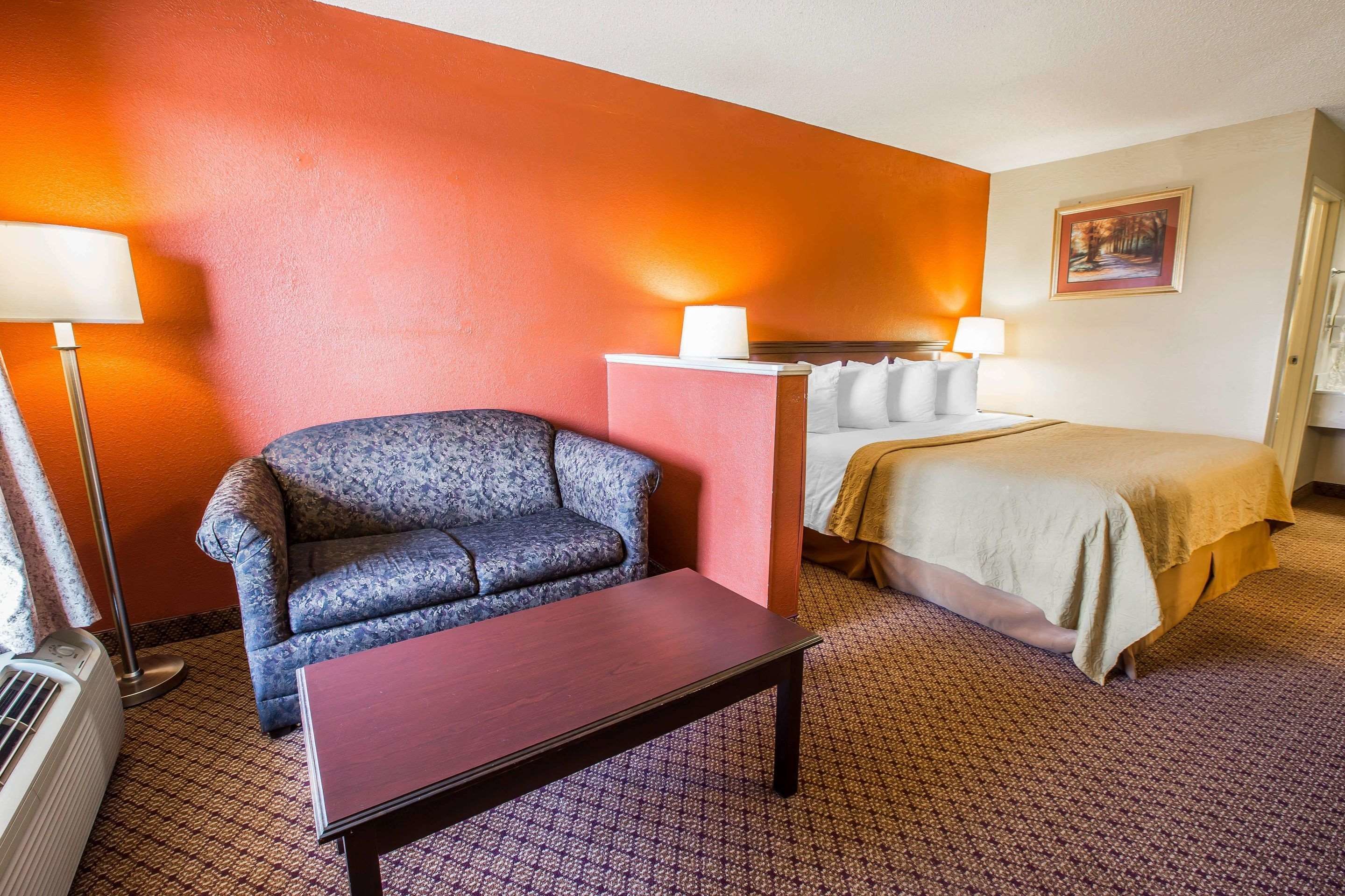 Una habitación de hotel con cama, sofá, mesa y un calentador portátil.