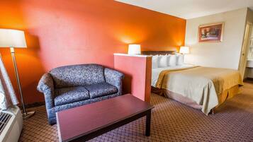 Una habitación de hotel con cama, sofá, mesa y un calentador portátil.