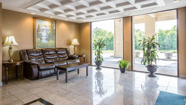 A lobby with a leather sofa, two lamps, a painting, and potted plants. - Quality Inn Gaffney I-85 (Gaffney)