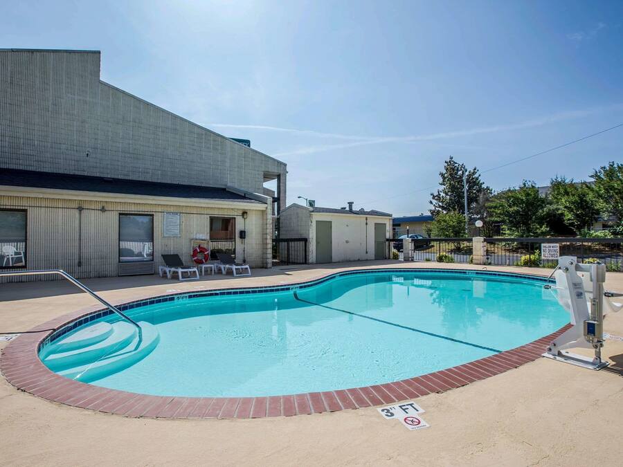 A swimming pool with a brick edge, a metal ladder, and a sign indicating a 3' height limit.
