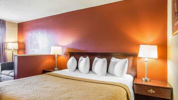 Una habitación de hotel con una cama grande, un cabecero de madera y dos mesitas de noche con lámparas.
