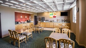 A dining area with a high ceiling, wooden chairs, a table, and a kitchen area with a TV and food display. - Quality Inn Gaffney I-85 (Gaffney)