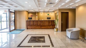A hotel lobby with a reception desk, a waiting area with a chair, and a large window providing a view of the outside. - Quality Inn Gaffney I-85 (Gaffney)
