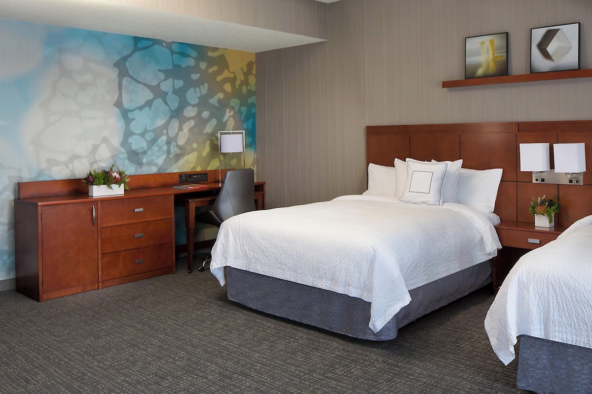 A hotel room with a bed, a desk, a chair, and a nightstand.