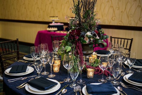 Une table dressée pour un dîner formel, avec de la vaisselle transparente, des serviettes pliées et des chandeliers.