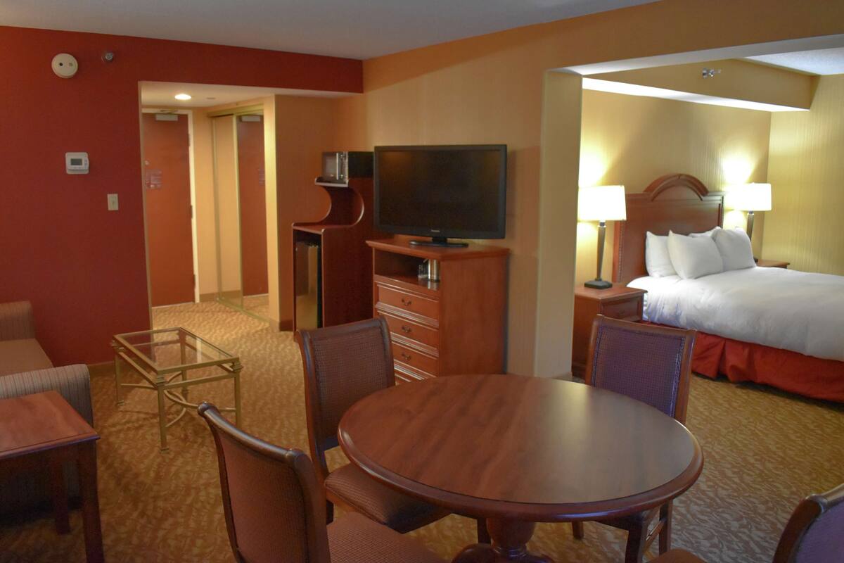 Quarto de hotel com cama, televisão, escrivaninha e cadeira.