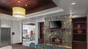 Eine moderne Lobby mit Kamin aus Stein, bequemen Sitzgelegenheiten und einem an der Wand befestigten Fernseher.