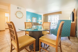 Un comedor con una mesa de vidrio, sillas de madera y una pared azul.