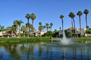 A hotel with a pool, palm trees, and a fountain. - Desert Breezes Resort (Palm Desert)