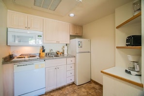 A compact kitchen with white appliances, including a microwave, refrigerator, and dishwasher.