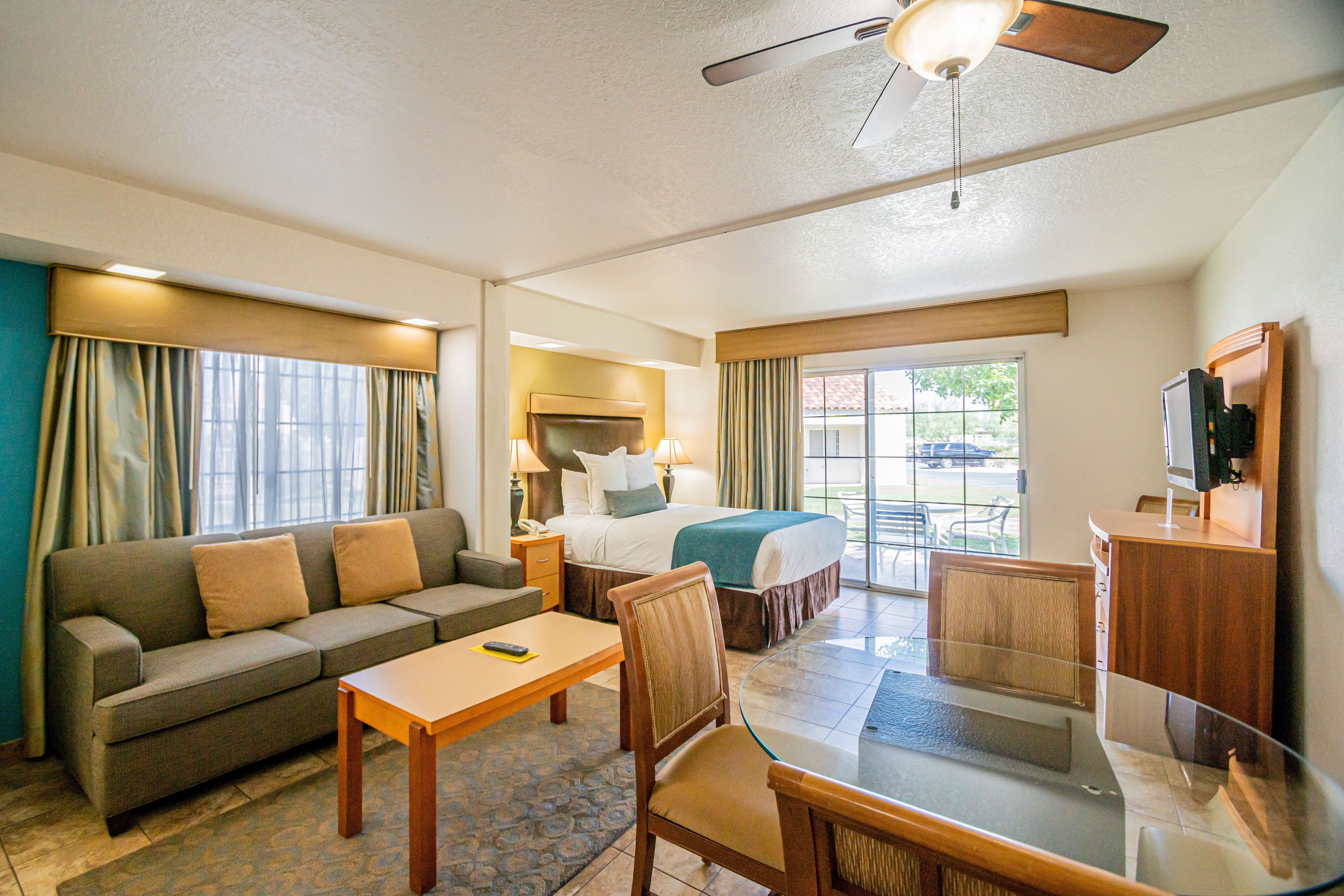A hotel room with a sofa, a bed, a desk, a chair, and a television.