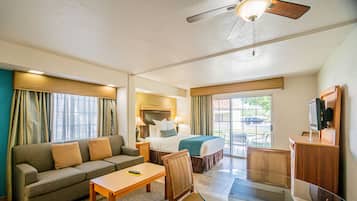 A hotel room with a sofa, a bed, a desk, a chair, and a television.