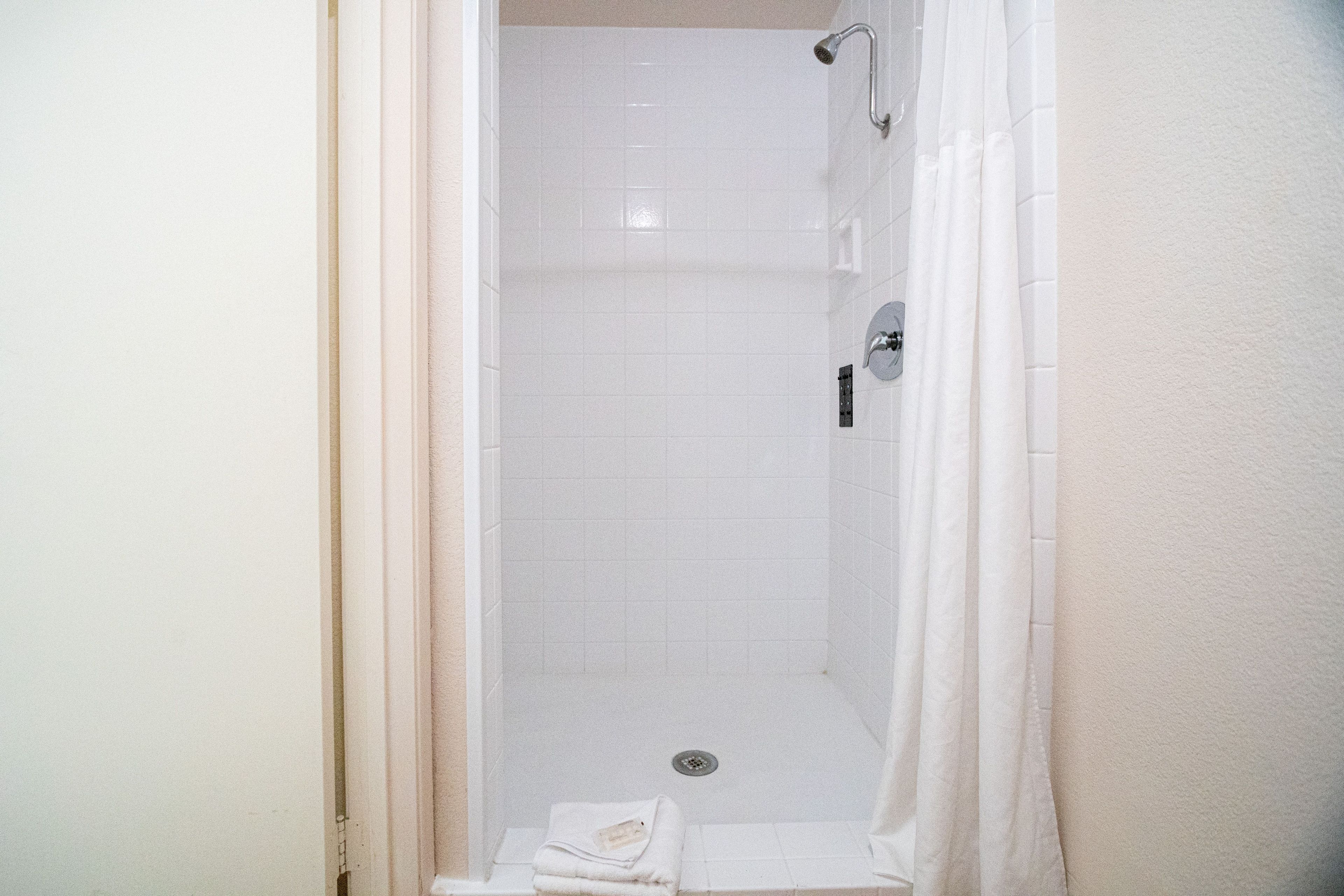 Eine Dusche mit Glastür, Brausekopf und Handtuchhalter.