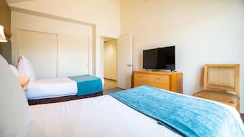 A hotel room with two beds, a TV on a wooden dresser, and a chair.