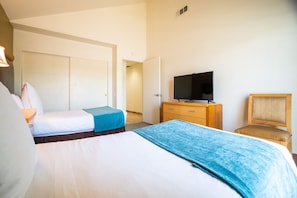 A hotel room with two beds, a TV on a wooden dresser, and a chair.