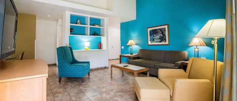 Ein Wohnzimmer mit blauer Wand, einem Sofa, einem Sessel, einem Couchtisch und einem Fernseher.