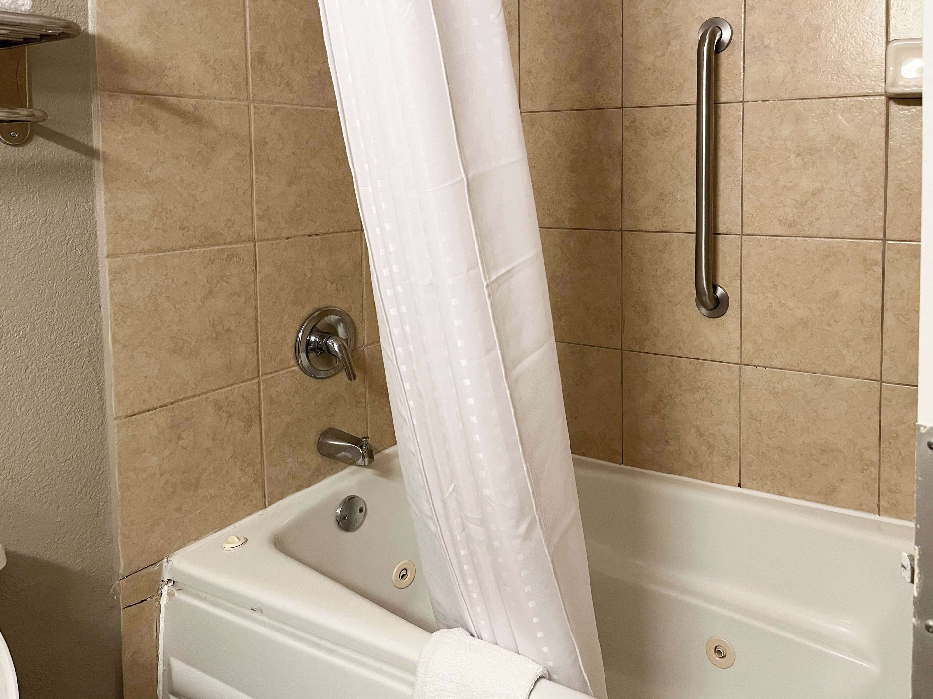 A bathtub with a shower curtain, a grab bar, and a towel rack.