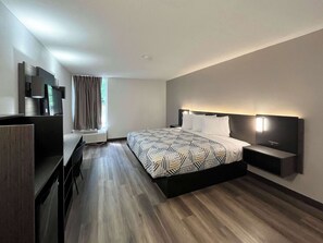 A modern hotel room with a large bed, a desk, and a TV.