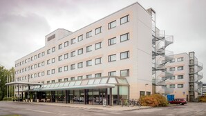 A multi-story hotel with a covered entrance, a parking area, and a fire escape. - Scandic Veromies (Vantaa)